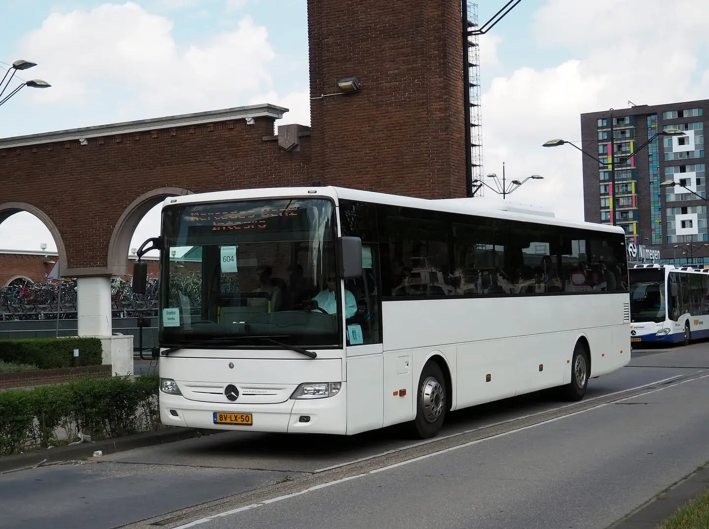 Bus van RT Reizen op een oprit, met tuin en bomen eromheen.
