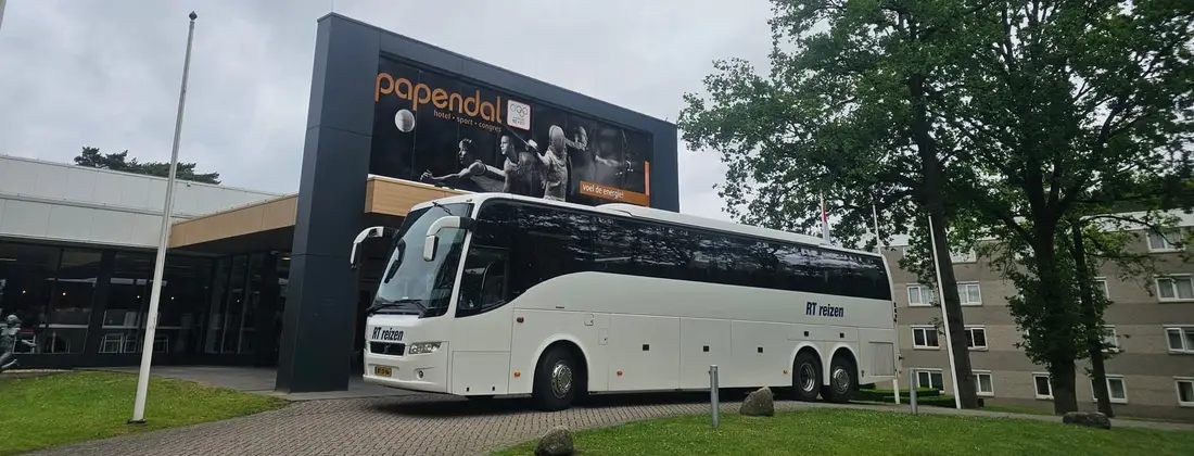 Touringcar van RT Reizen voor de ingang van sportcentrum Papendal in Arnhem.