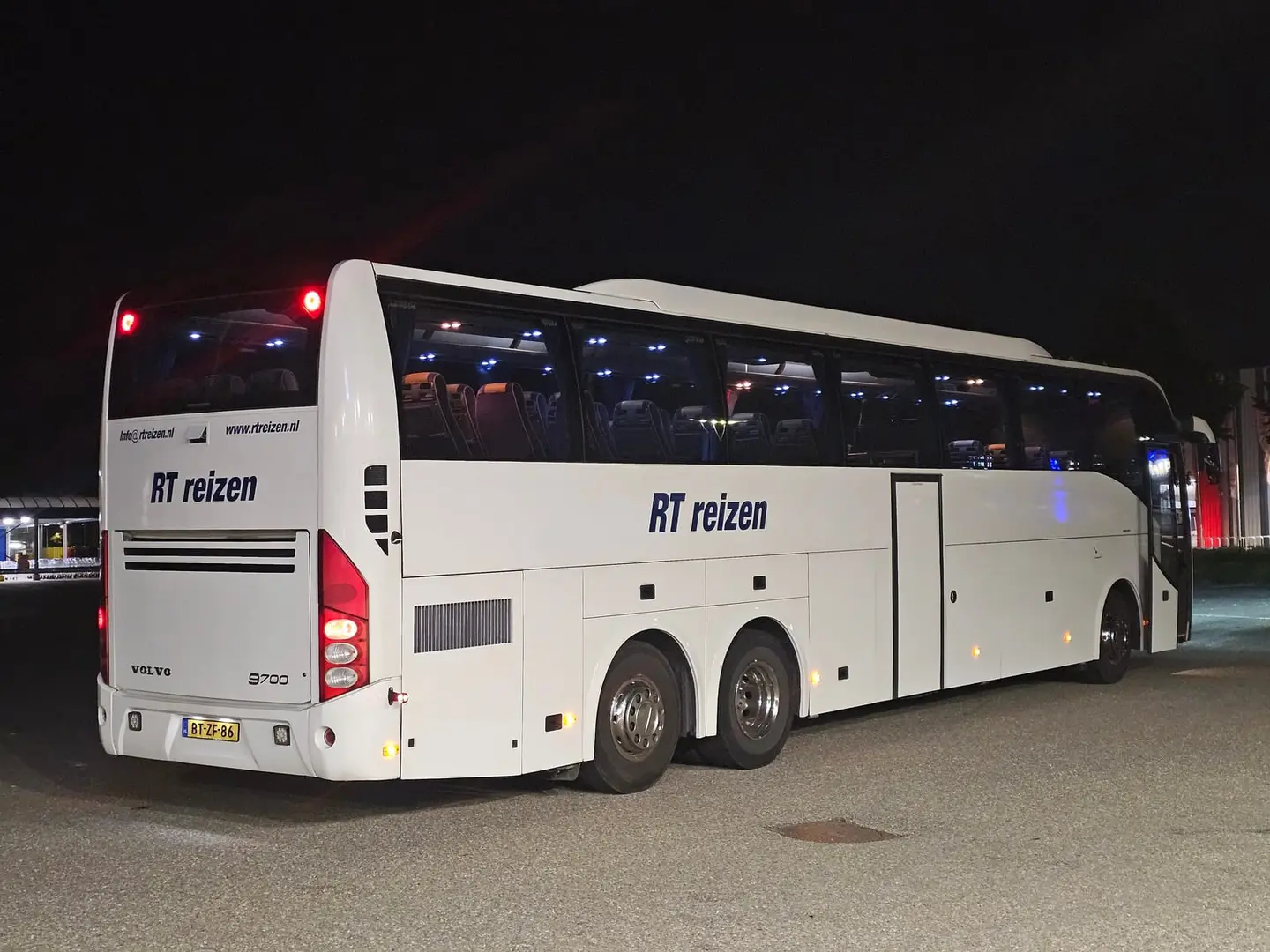 Touringcar van RT Reizen van achteren op de parkeerplaats, met het woordmerk op de zijkant.