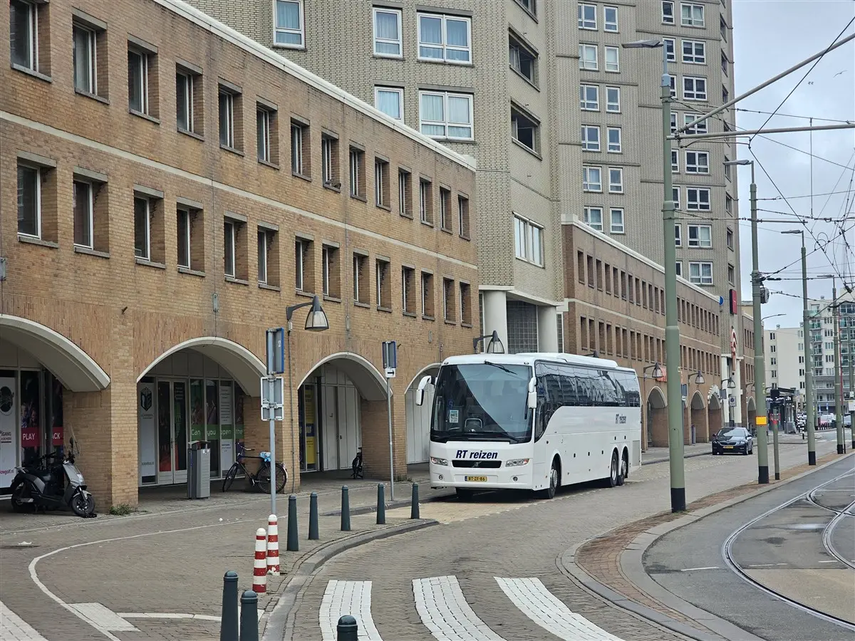 Touringcar van RT Reizen langs de stoep in een stadsstraat.