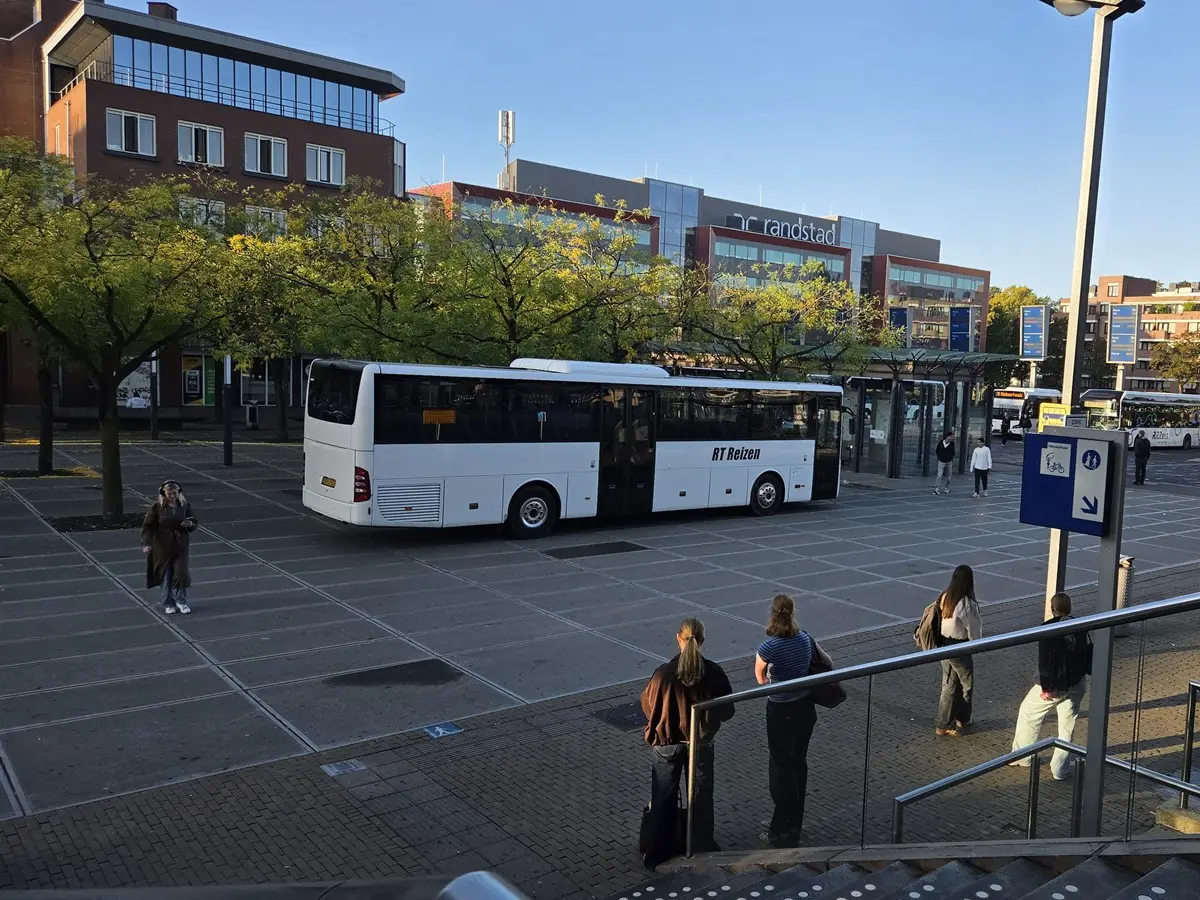 Bus van RT Reizen op een busplein bij een station.